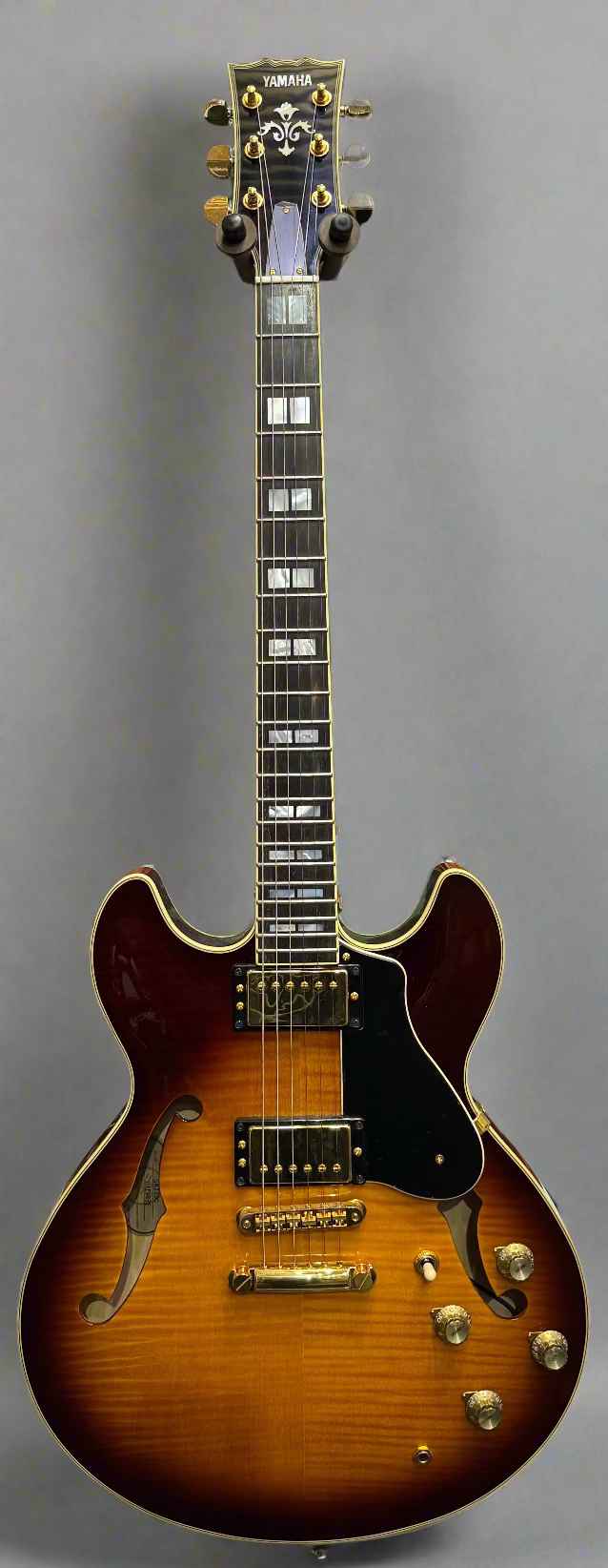 Electric guitar with a green and brown finish against a wall of other guitars
