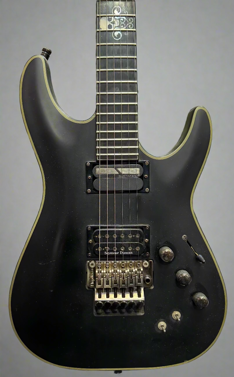 Black electric guitar with green pickguard against a brick wall background