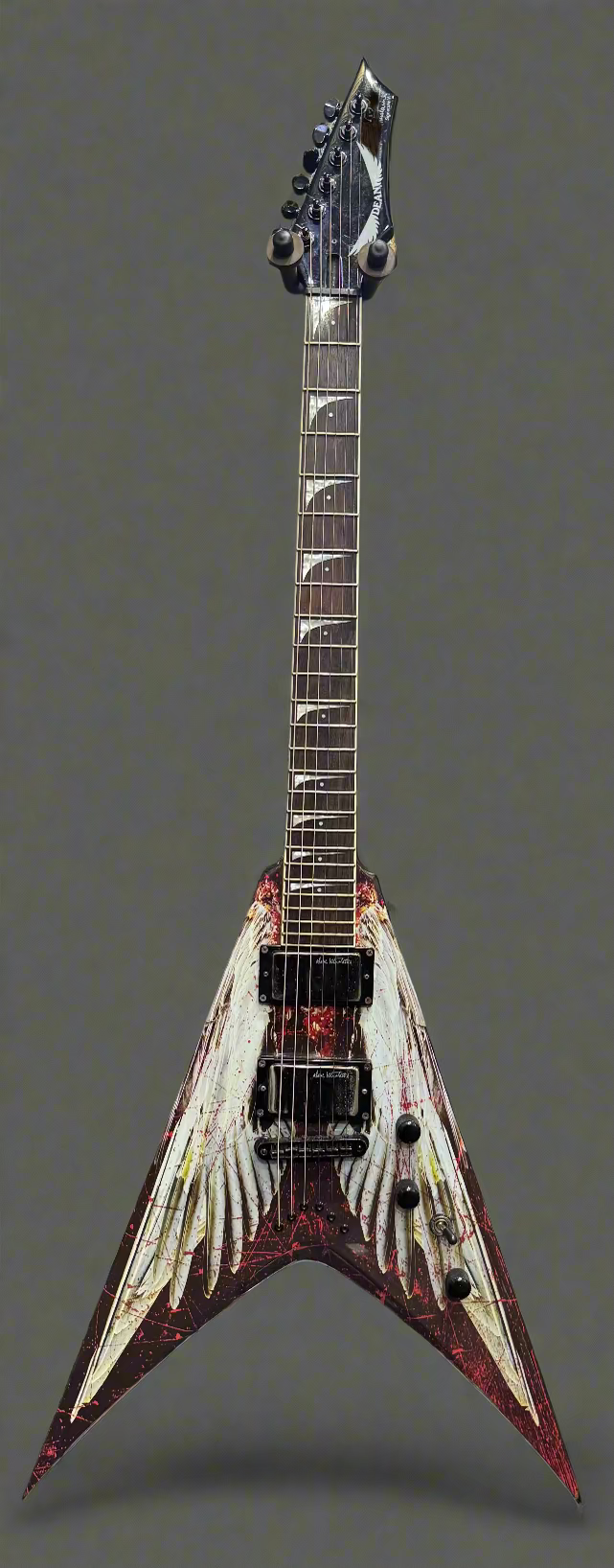 Fancy electric guitar with a unique design in front of a wall of other guitars