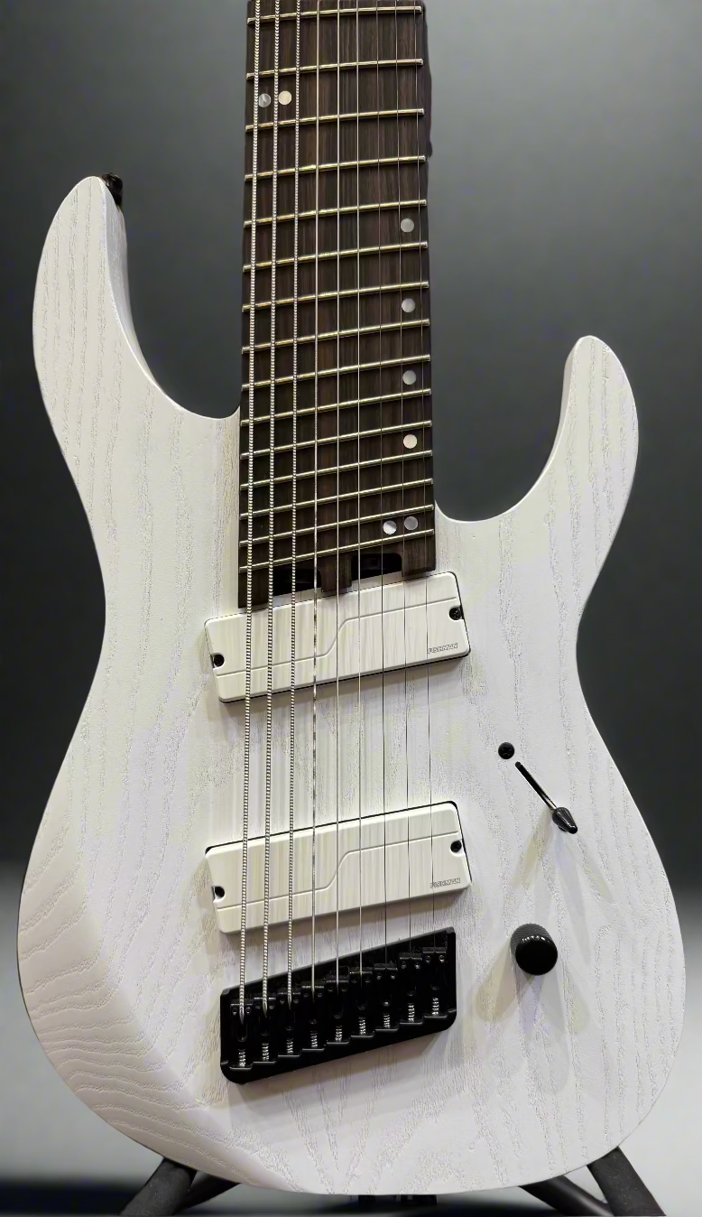 White electric guitar with a blurred background of musical equipment