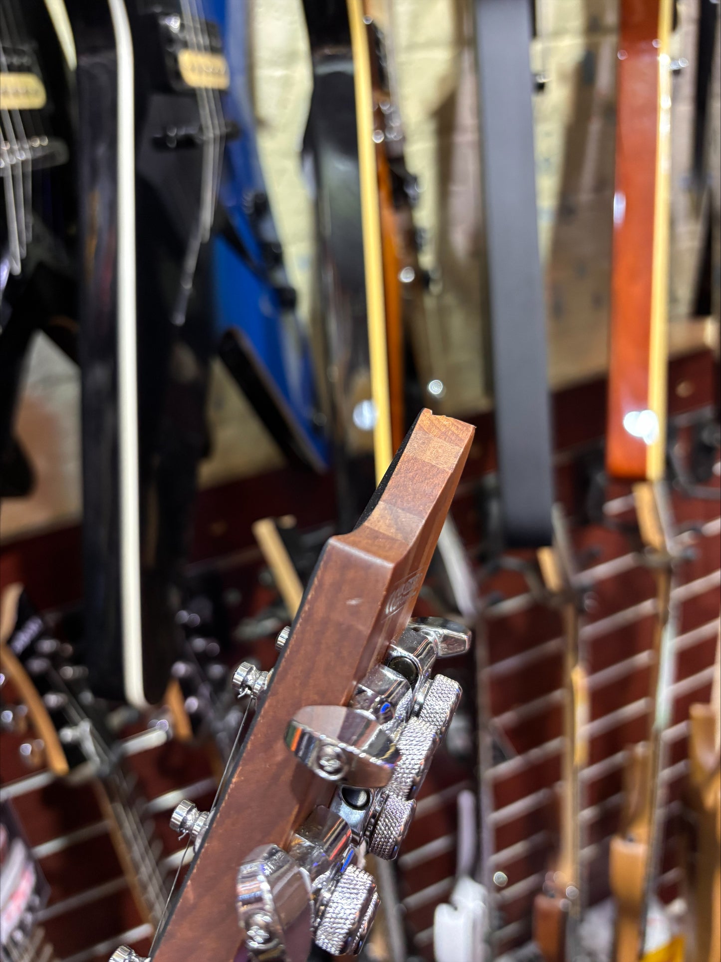 Close-up of guitar necks with focus on the headstock in a store setting