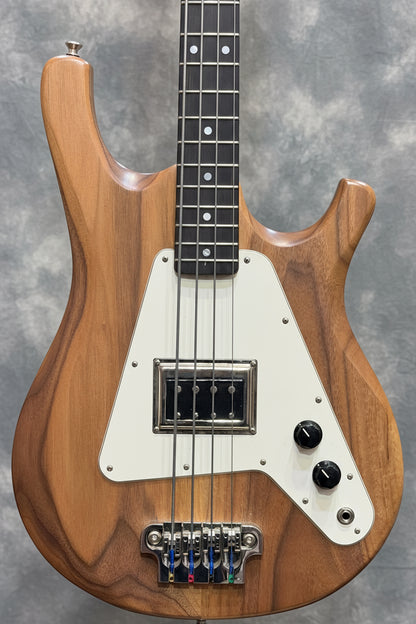 Wooden bass guitar with a white pickguard against a guitar rack background