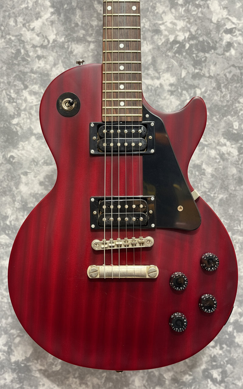Red electric guitar with a green pickguard on a wooden background