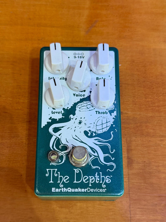 Guitar effects pedal with 'The Depths' branding on a wooden surface