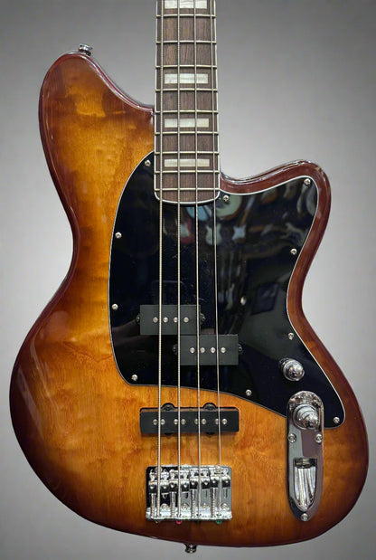 Electric bass guitar with a sunburst finish against a background of other guitars