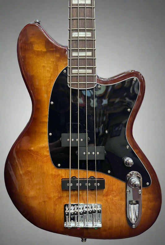 Electric bass guitar with a sunburst finish against a background of other guitars