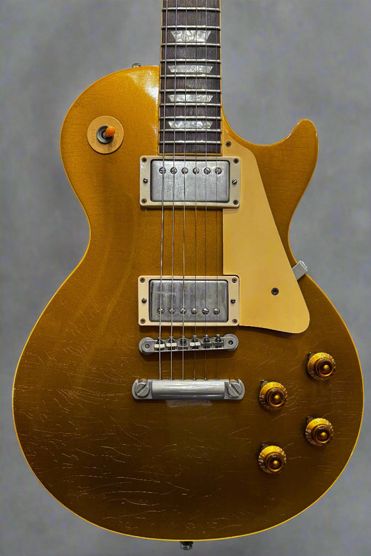 Gold electric guitar with a reflective surface in a guitar store setting