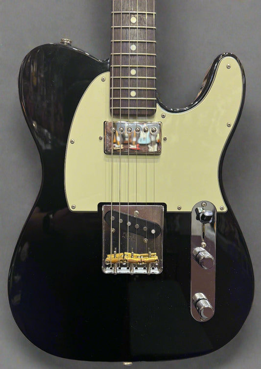 Black electric guitar with cream pickguard on a stand against a brick wall background