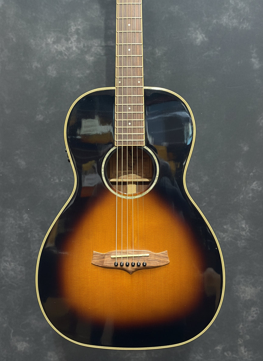 Acoustic guitar with a sunburst finish on a guitar rack.