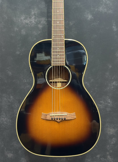 Acoustic guitar with a sunburst finish on a guitar rack.