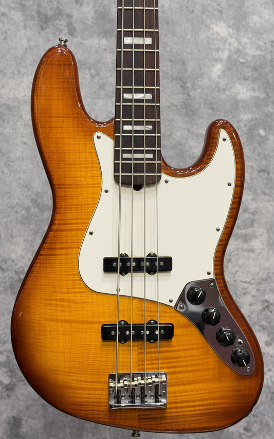 Close-up of a bass guitar with a sunburst finish on a wooden background
