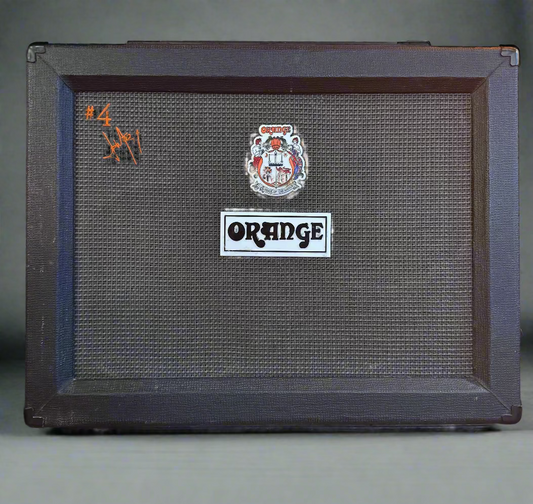 Orange guitar amplifier cabinet with a sticker on a dark background