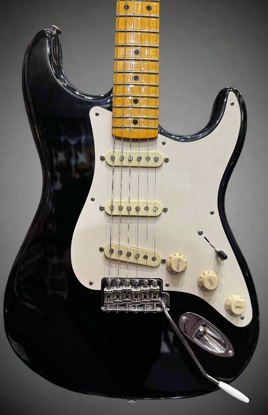 Black electric guitar with a white pickguard in a guitar shop setting
