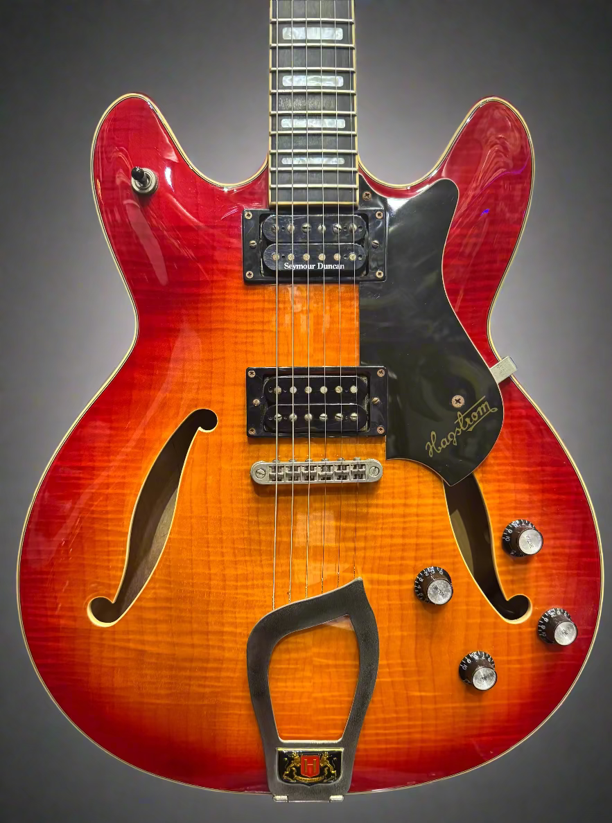 Close-up of a red electric guitar with a blurred background of other guitars