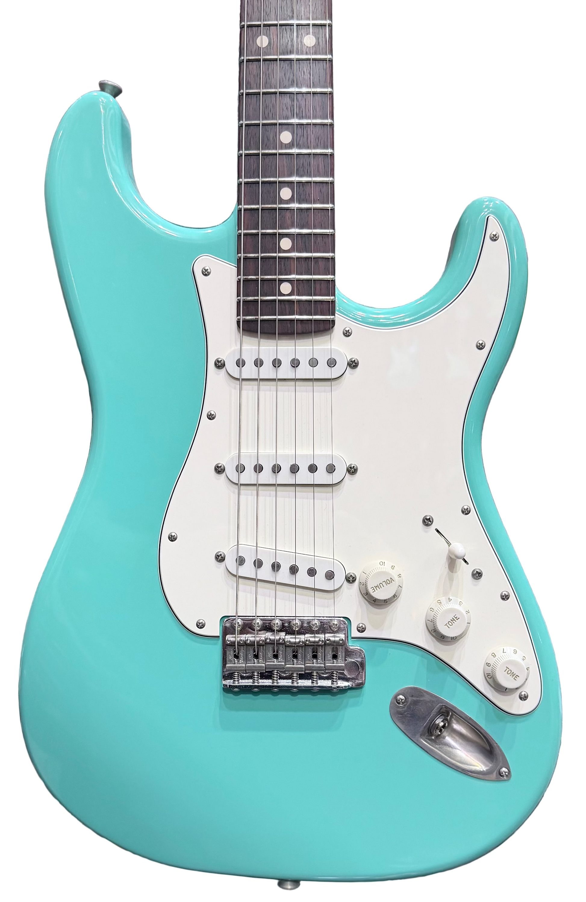 Turquoise electric guitar with white pickguard against a background of other guitars
