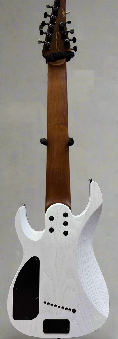 White electric guitar body with a brown neck against a background of amplifiers and guitars.
