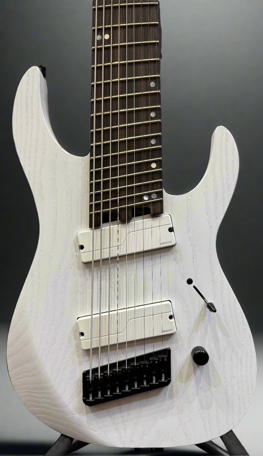 White electric guitar with a blurred background of musical equipment