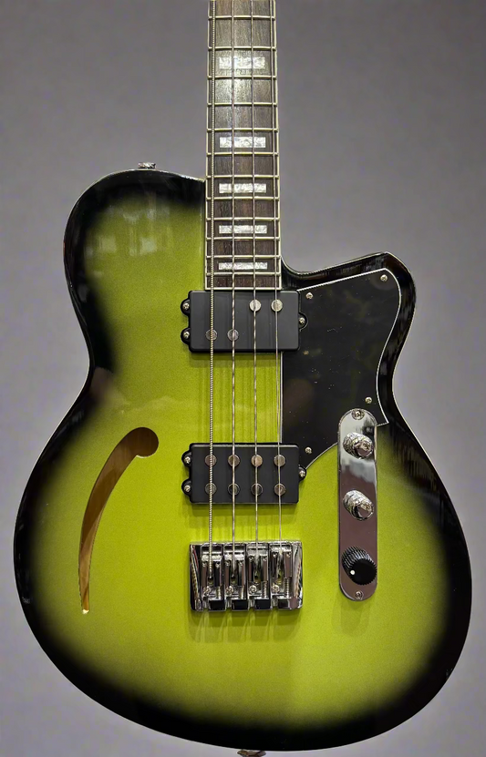 Green electric guitar with black pickguard and hardware against a brick wall.