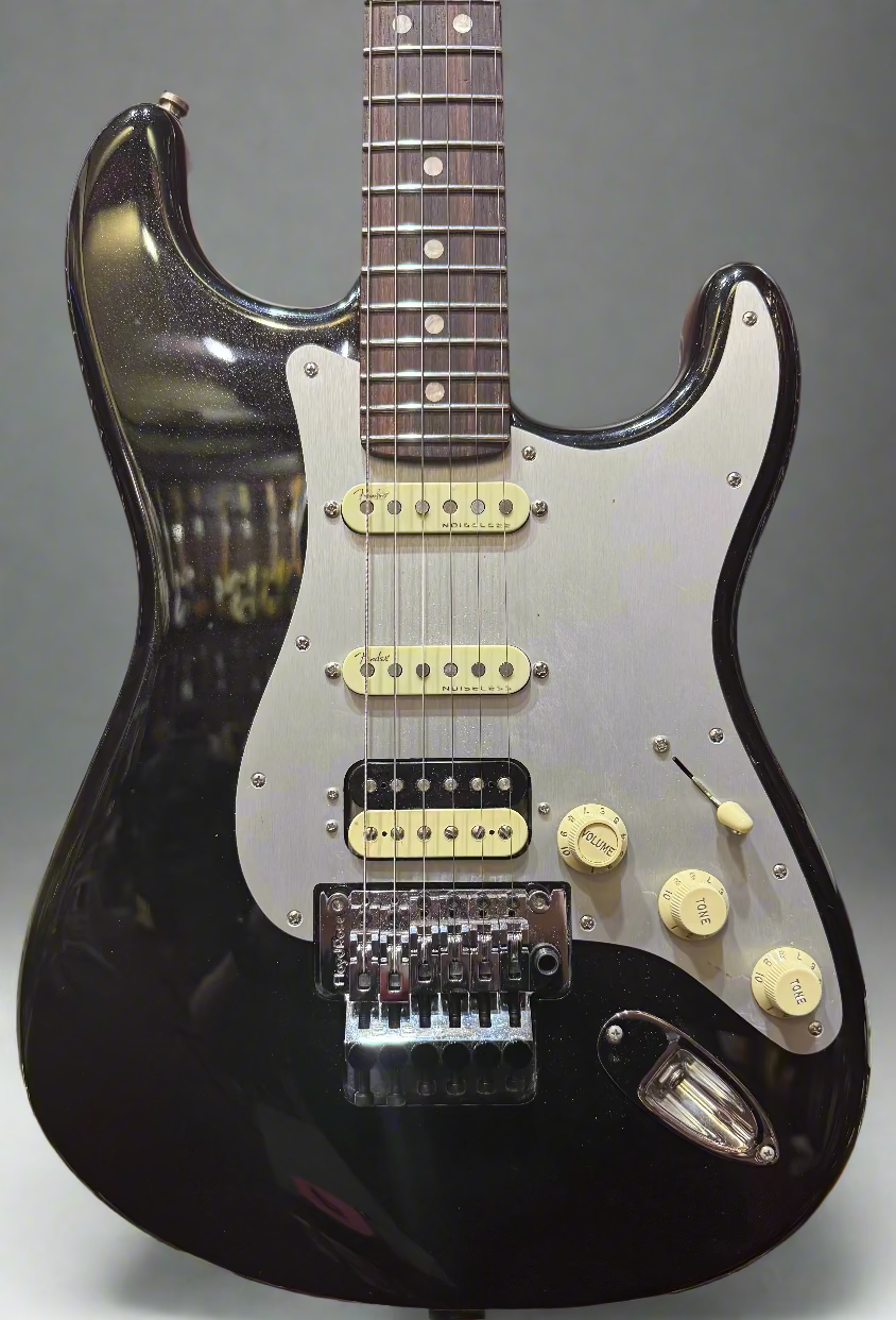 Black electric guitar with a white pickguard on a wooden background