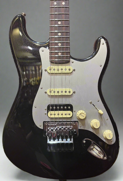 Black electric guitar with a white pickguard on a wooden background