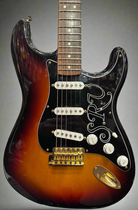 Electric guitar with sunburst finish and black pickguard in a guitar shop setting