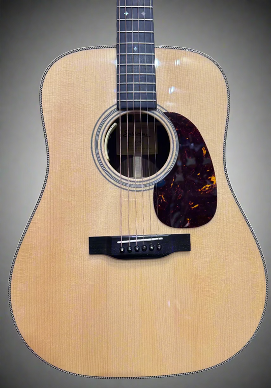 Acoustic guitar with a tortoiseshell pickguard on a gray background