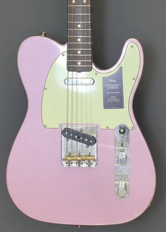 Electric guitar with a pink body and light green neck on a gray background
